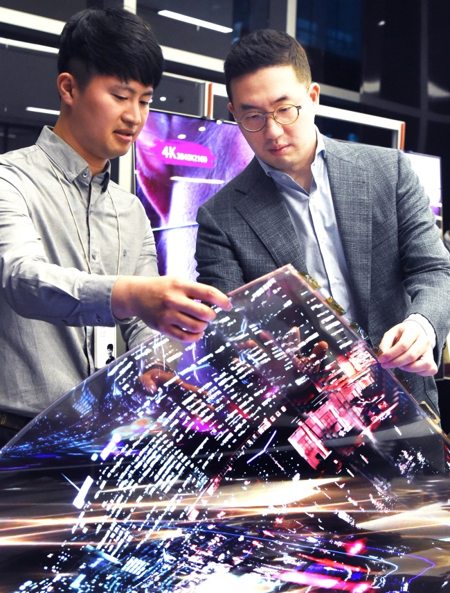 LG Chairman Koo Kwang-mo (right) looks at an organic light-emitting diode display at LG Science Park in Magok, northwestern Seoul, in September.