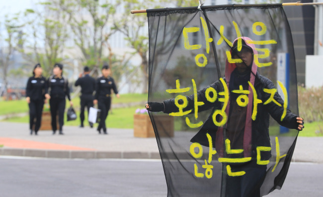 An activist stages a protest Tuesday against the International Fleet Review with a sign that reads, "You are not welcomed." Yonhap