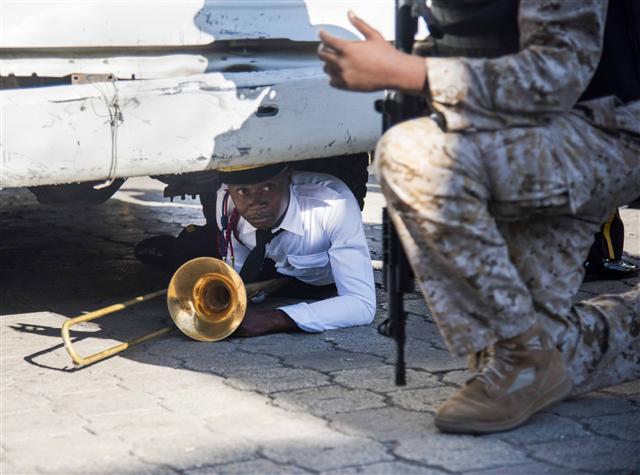 <YONHAP PHOTO-3885> epaselect epa07100666 A member of the National Palace's music band shelters under a truck as a riot breaks out during the commemoration of the 212 anniversary of the murder of Jean Jacques Dessalins, in Port-au-Prince, Haiti, 17 October 2018. Several individuals threw stones during a commemoration event of the 212 anniversary of the murder of Jean Jacques Dessalins, founding father of Haiti, chaired by Haitian President Moise, at the Dessalins monument, to which the presidential security responded by shooting. EPA/Jean Marc Herve Abelard EPA/JEAN MARC HERVE ABELARD/2018-10-18 07:08:55/ <저작권자 ⓒ 1980-2018 ㈜연합뉴스. 무단 전재 재배포 금지.>