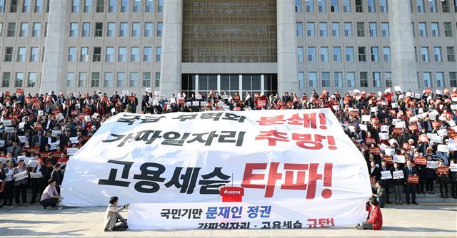 일부 공공기관의 ‘고용세습’ 논란과 관련해 현 정부 비정규직 정책 전반에 대한 재검토를 촉구하는 목소리가 높아지고 있다. 자유한국당 당직자와 당원들이 지난 21일 국회 본청 앞에서 열린 ‘국가기만 문재인 정권의 가짜 일자리ㆍ고용세습 규탄대회’에서 대형 현수막을 펼치는 퍼포먼스를 하고 있다.  [연합뉴스]