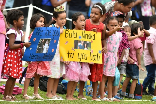 Fijian children hold banners to welcome Prince Harry and his wife Meghan (AFP)