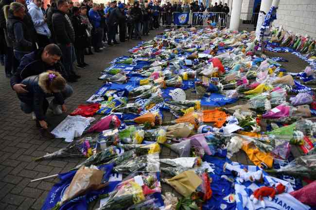 People add flowers to a growing pile of tributes outside Leicester City Football Club's King Power Stadium in Leicester, eastern England, on Sunday after a helicopter belonging to the club's Thai chairman Vichai Srivaddhanaprabha crashed outside the stadium the night before. (AFP-Yonhap)