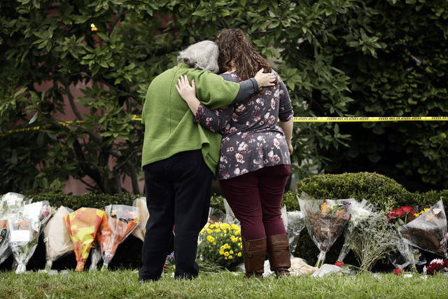 Two people support each other in front of flowers at a makeshift memorial at the Tree of Life Synagogue in Pittsburgh, Sunday, Oct. 28, 2018 (AP)