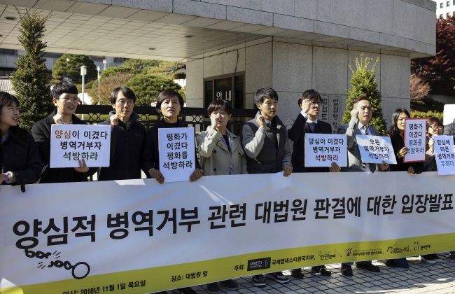Human rights activists hold a sign that says "Peace has won" among others, in front of the Supreme Court in Seoul, Thursday. (Yonhap)