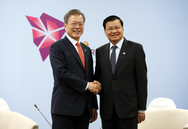 President Moon Jae-in and Prime Minister of Laos Thongloun Sisoulith shake hands ahead of their meeting in Singapore on Wednesday. Yonhap