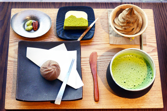 Mochibang serves treats like chestnut ohagi (front, left), which features a marron glace coated in bean paste infused with marron glace syrup; creamy swirls of hojicha ice cream topped with powdered hojicha (back, right); and a steamed bean paste cake called ukishima (back, center). Treats can be paired with frothy bowls of matcha (front, right) or enjoyed with tidbits like candied nuts (back, left). (Photo credit: Park Hyun-koo/The Korea Herald)
