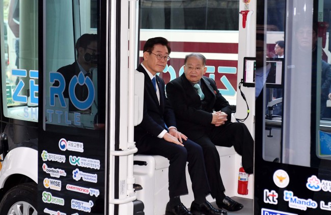 Gyeonggi Gov. Lee Jae-myung, left, and Ri Jong-hyok, vice chairman of North Korea’s Korean Asia-Pacific Peace Committee, ride the Zero Shuttle, an unmanned shuttle bus, at the Pangyo Techno Valley’s Startup Campus in Seongnam, Gyeonggi on Nov. 15. (Yonhap)