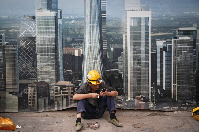 <YONHAP PHOTO-0357> FILE- In this Sept. 19, 2018, file photo a worker browses his smartphone outside a construction site wall depicting the skyscrapers in the Chinese capital at the Central Business District in Beijing. After galloping along for the past two years, the global economy is showing signs of weakening, with the United States, China and Europe all facing the rising threat of a slowdown. Few economists foresee an outright global recession within the next year. But the synchronized growth that powered most major economies since 2017 appears to be fading. (AP Photo/Andy Wong, File)/2018-11-21 03:51:20/ <저작권자 ⓒ 1980-2018 ㈜연합뉴스. 무단 전재 재배포 금지.>
<YONHAP PHOTO-0357> FILE- In this Sept. 19, 2018, file photo a worker browses his smartphone outside a construction site wall depicting the skyscrapers in the Chinese capital at the Central Business District in Beijing. After galloping along for the past two years, the global economy is showing signs of weakening, with the United States, China and Europe all facing the rising threat of a slowdown. Few economists foresee an outright global recession within the next year. But the synchronized growth that powered most major economies since 2017 appears to be fading. (AP Photo/Andy Wong, File)/2018-11-21 03:51:20/ <저작권자 ⓒ 1980-2018 ㈜연합뉴스. 무단 전재 재배포 금지.>