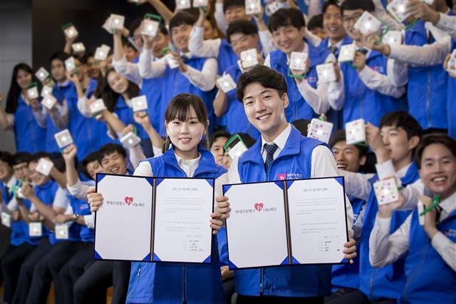 현대오일뱅크 신입사원들이 에너지 빈곤 국가에 보낼 태양광 랜턴을 조립하고 급여 1% 나눔 약정서에 사인한 후 포즈를 취하고 있다.