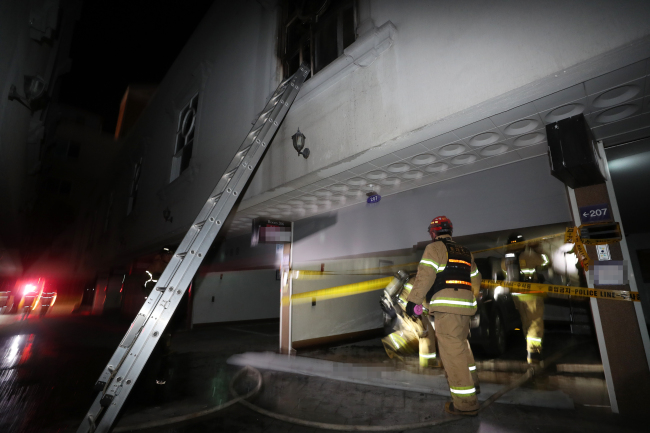 Firefighters on Sunday conduct an on-site investigation of an unmanned motel in Yeosu, South Jeolla Province, where two people were killed in a fire. (Yonhap)