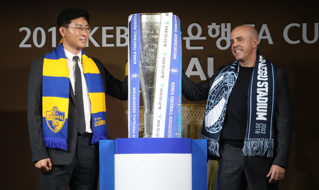 Ulsan Hyundai FC head coach Kim Do-hoon (L) and Daegu FC head coach Andre Luiz Alves Santos pose for a photo with the Korea Football Association (KFA) Cup winners' trophy at the KFA House in Seoul on Dec. 3, 2018. (Yonhap)