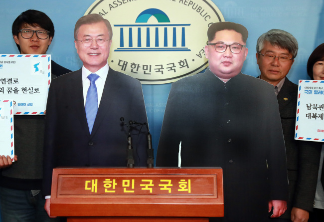 Groups calling for end to North Korean sanctions hold up cutouts of President Moon Jae-in and North Korean leader Kim Jong-un at the National Assembly on Nov. 28. Yonhap