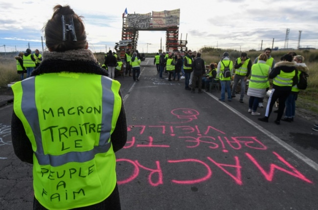 Yellow vest protesters have blocked fuel depots like this one in Frontignan, southern France, where a woman's vest reads 'Macron, traitor, the people are hungry' (AFP)