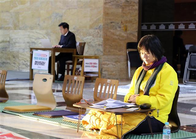 더불어민주당 홍영표, 자유한국당 김성태 원내대표가 김동연 부총리 겸 기획재정부 장관과 함께 6일 오후 국회에서 내년도 예산안 합의 결과를 발표하고 손을 맞잡고 있다. (왼쪽) 민주당과 한국당의 예산처리 강행에 반대하며 단식농성에 들어간 정의당 이정미 대표가 7일 오전 국회 로텐더홀에서 농성을 계속하고 있다. 뒷쪽은 역시 같은 이유로 단식농성 중인 바른미래당 손학규 대표.  [연합뉴스]