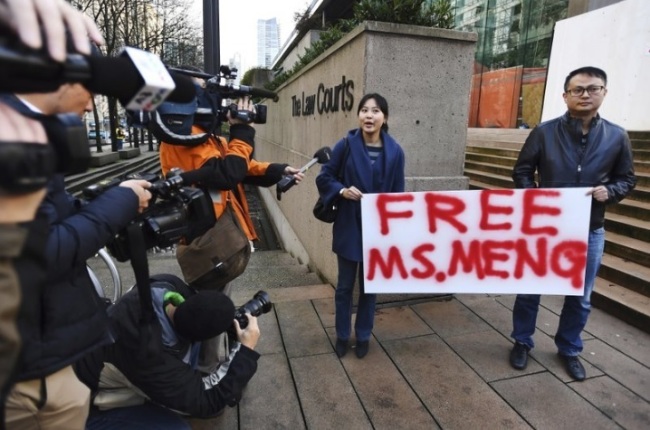 People hold a sign at a Vancouver, British Columbia courthouse prior to the bail hearing for Meng Wanzhou, Huawei's chief financial officer on Monday, December 10, 2018. Meng Wanzhou was detained at the request of the US during a layover at the Vancouver airport on Dec. 1. (The Canadian Press-AP)