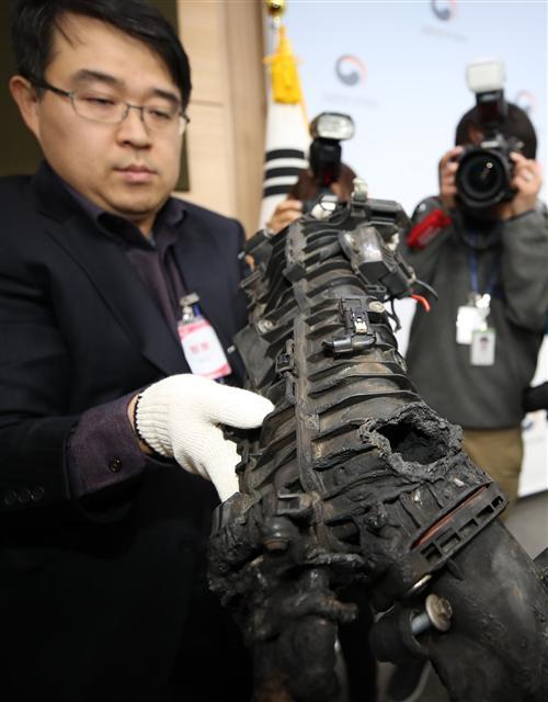 24일 오전 서울 종로구 도렴동 정부서울청사에서 한국교통안전공단 관계자가 BMW 사고차량의 구멍난 EGR 쿨러를 들어보이고 있다. 민관합동조사단은 EGR쿨러 균열로 인한 냉각수 누수가 화재 발생원인이나 EGR 설계결함으로 냉각수 끓음 현상(보일링)을 확인했다고 밝혔다. [연합뉴스]