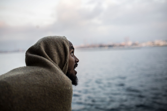 A migrant looks out as they approach port, from the deck of the Spanish NGO Proactiva Open Arms rescue vessel, after being rescued in the Central Mediterranean Sea on Dec. 21 before disembarking in the port of Crinavis in Algeciras, Spain, Friday, Dec. 28, 2018. (AP-Yonhap)