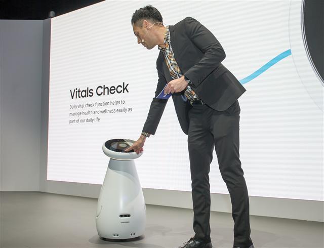 삼성전자가 CES 2019에서 최초 공개한 ‘삼성봇 케어’. 삼성봇 케어가 사람의 맥박과 혈압을 측정하고 있는 모습(사진 왼쪽). 삼성전자 부스에서 삼성전자 모델이 개인에게 최적화된 환경과 인포테인먼트 시스템을 제공하는 차량용 ‘디지털 콕핏 2019’를 시연하고 있다. [제공=삼성전자]