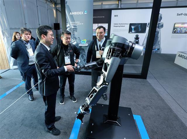 9일(현지시간) CES 2019 네이버 부스를 방문한 노진서 LG전자 로봇사업센터장(전무, 왼쪽에서 세번째)을 비롯한 관계자들이 네이버랩스 석상옥 헤드(맨 오른쪽)로부터 세계 최초로 5G 기술을 적용한 브레인리스로봇 ‘앰비덱스’의 설명을 듣고 있다. [제공=네이버]