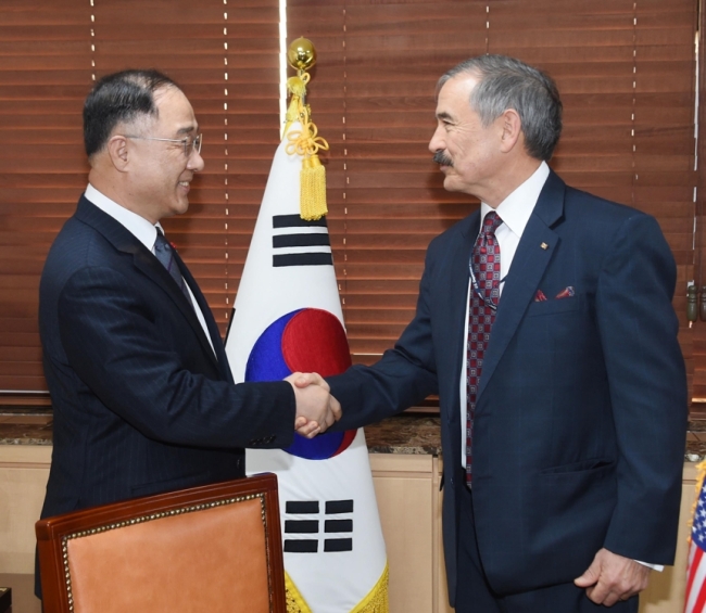 Hong Nam-ki (L), the minister of economy and finance, shakes hands with US Ambassador to South Korea Harry Harris ahead of their talks at the government complex building across from the US Embassy in central Seoul on Jan. 11, 2019. This photo was provided by the Ministry of Economy and Finance. (Yonhap)