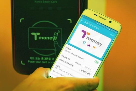 승객이 버스를 타면서 휴대전화를 단말기에 태그하고 있다.