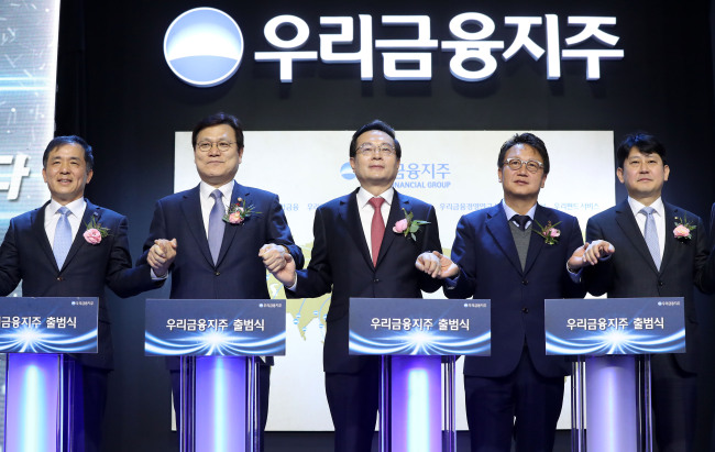 Sohn Tae-seung (third from left), chairman of Woori Finance Holdings and Woori Bank, poses at a ceremony to mark the bank’s official transformation into a financial holding company at the Woori Bank headquarters in central Seoul, Monday. From left: Korea Deposit Insurance Corp. CEO Wi Seong-bak; Financial Services Commission Chairman Choi Jong-ku; Woori Financial Holdings Chairman Sohn; Rep. Min Byung-doo of the ruling Democratic Party of Korea; and Yoo Kwang-yeol, first senior deputy governor of the Financial Supervisory Service. (Yonhap)