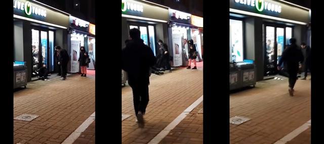 지난 13일 오후 서울 지하철 암사역 3번 출구 앞 인도에서 박모 군이 쓰러진 채 한모 군에게 폭행 당하는 가운데 이명은(사진 뒷모습)씨가 이를 말리려 달려가고 있다.  [사진=목격자 동영상 캡처]
