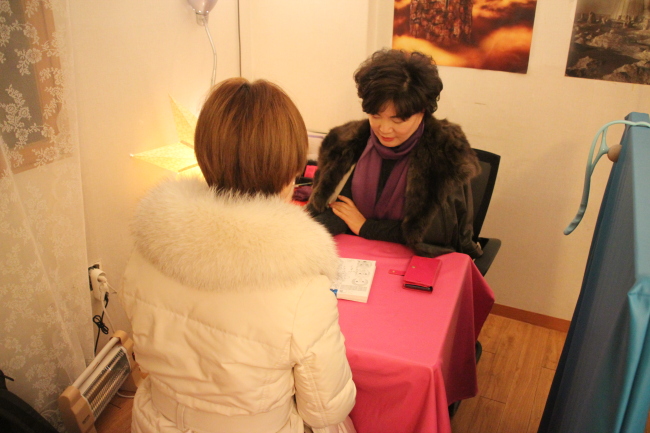 Fortune-teller reads saju, or four pillars, for a customer. (Lim Jeong-yeo/The Korea Herald)