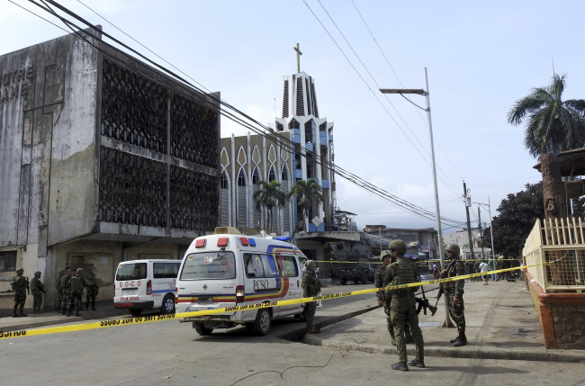 Police investigators and soldiers attend the scene after two bombs exploded outside a Roman Catholic cathedral in Jolo, the capital of Sulu province in southern Philippines, Sunday. AP