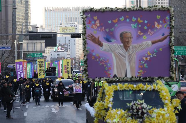 일본군 위안부 피해자 고 김복동 할머니의 발인식이 엄수된 1일 오전 추모행렬이 서울광장을 출발해 일본대사관으로 향하고 있다. 양팔을 벌리고 환한 표정을 짓는 김 할머니의 대형사진 뒤로 시민들이 함께 행진하며 고인의 마지막 길을 배웅했다.  				 [연합]