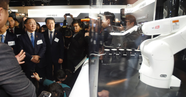 　Deputy Prime Minister and Finance Minister Hong Nam-ki (left) along with other Cabinet members and officials attend an event arranged by KT to explain various technologies and contents using 5G at Gwacheon KT headquarters on Wednesday.  Yonhap