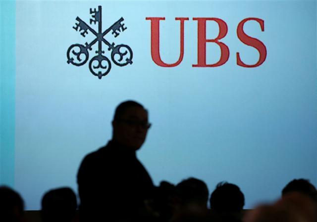 UBS 로고 앞에서 한 사람이 걸어가고 있다. [로이터]