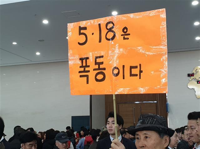 지난 21일 부산 벡스코에서 열린 자유한국당 전당대회 합동연설회에 참가한 한 지지자가 ‘5ㆍ18은 폭동이다’란 내용의 피켓을 들고 1인 시위를 하고 있다(왼쪽). 연설회장 앞에서 당 대표 후보인 황교안 전 국무총리 지지자들이 사물놀이를 하며 유세에 나서고 있다. 뒤에는 5ㆍ18 망언을 규탄하는 시민단체의 기자회견이 동시에 진행되고 있다.  [유오상 기자/osyoo@]
