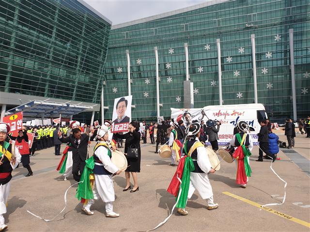 지난 21일 부산 벡스코에서 열린 자유한국당 전당대회 합동연설회에 참가한 한 지지자가 ‘5ㆍ18은 폭동이다’란 내용의 피켓을 들고 1인 시위를 하고 있다(왼쪽). 연설회장 앞에서 당 대표 후보인 황교안 전 국무총리 지지자들이 사물놀이를 하며 유세에 나서고 있다. 뒤에는 5ㆍ18 망언을 규탄하는 시민단체의 기자회견이 동시에 진행되고 있다.  [유오상 기자/osyoo@]