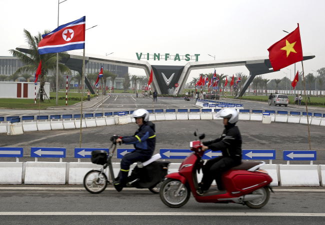 People ride motorcycles outside VinFast, automotive startup manufacturer, with flags of North Korea, left, and Vietnam in Haiphong, northeastern Vietnam, Wednesday. (AP)