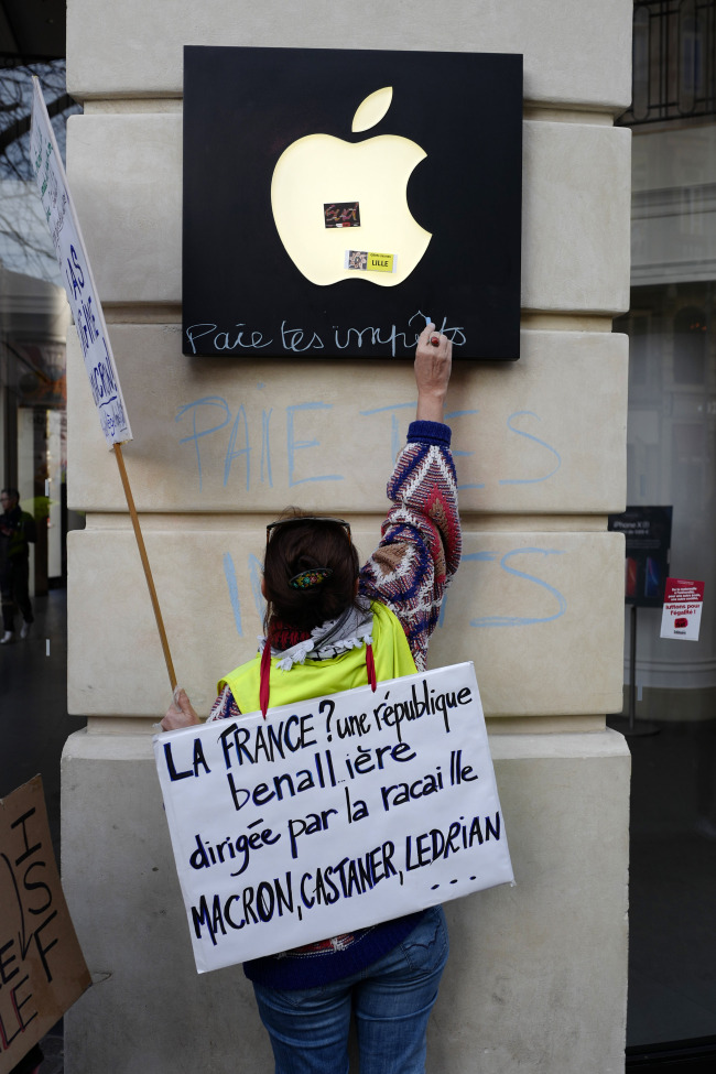 <YONHAP PHOTO-0231> Yellow vest protester writes on an Apple logo sign "Pay your taxes", in front of an Apple store during a demonstration Saturday, Feb. 16, 2019, in Lille, Northern France. With sign reading " France, Republic, led by the rabble, Macron, Castaner, LeDrian", referring to President Macron, Minister of Interior Castaner and Foreign Minister Le Drian. Yellow vest protesters are holding scattered demonstrations around Paris and the rest of France amid waning support for their movement. (AP Photo/Michel Spingler)/2019-02-17 00:59:53/ <저작권자 ⓒ 1980-2019 ㈜연합뉴스. 무단 전재 재배포 금지.>
<YONHAP PHOTO-0231> Yellow vest protester writes on an Apple logo sign "Pay your taxes", in front of an Apple store during a demonstration Saturday, Feb. 16, 2019, in Lille, Northern France. With sign reading " France, Republic, led by the rabble, Macron, Castaner, LeDrian", referring to President Macron, Minister of Interior Castaner and Foreign Minister Le Drian. Yellow vest protesters are holding scattered demonstrations around Paris and the rest of France amid waning support for their movement. (AP Photo/Michel Spingler)/2019-02-17 00:59:53/ <저작권자 ⓒ 1980-2019 ㈜연합뉴스. 무단 전재 재배포 금지.>