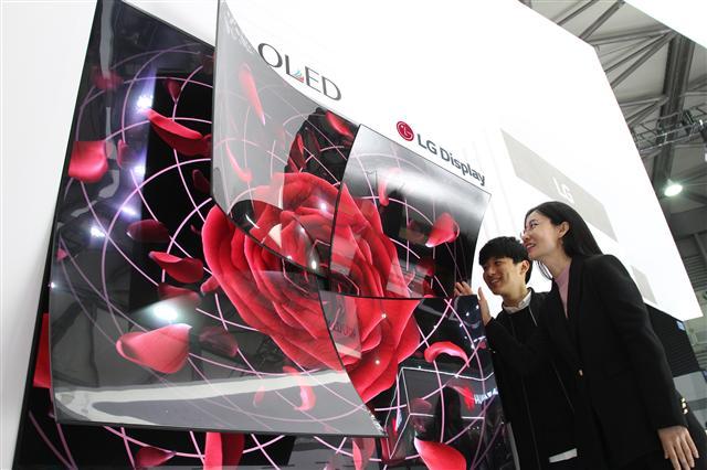 65인치 UHD OLED 디스플레이 4장을 이어 붙이고 끝부분을 둥글게 말아 장미꽃 모양을 형상화한 조형물을 관람객들이 보고 있다. [LG디스플레이 제공]