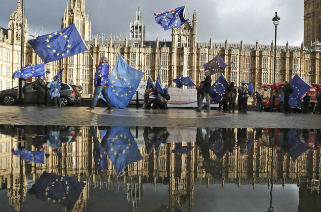 In this Monday, Dec. 3, 2018 file photo protestors are reflected in a puddle as they wave European flags to demonstrate against Brexit in front of the Parliament in London. (AP-Yonhap)