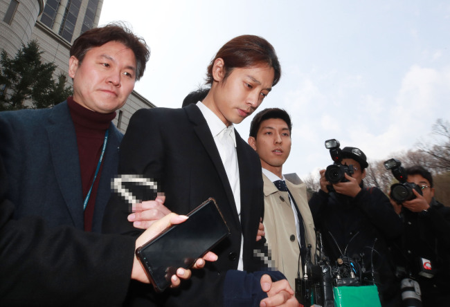 Police transfer singer Jung Joon-young (center) with his hands tied with a rope to Jongno Police Station after the warrant hearing at Seoul Central District Court on Thursday. (Yonhap)
