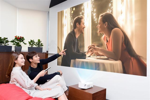LG전자 모델들이 2019년형 ‘LG 시네빔’ 프로젝터를 이용해 초대형 화면으로 영화를 시청하고 있다.  [LG전자 제공]