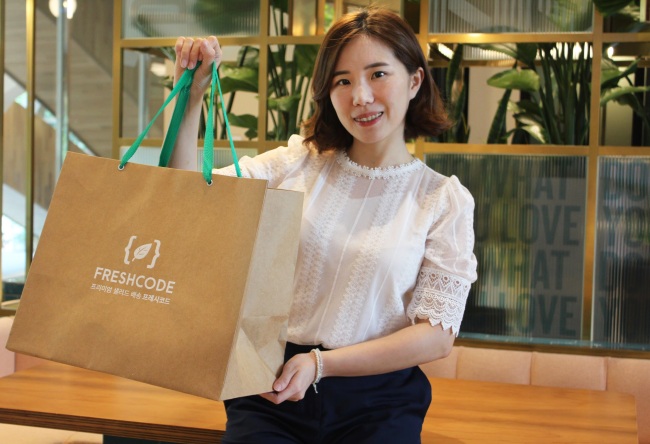 Regina Yoo, co-founder and CMO of Freshcode, poses with a bag of salads. (Freshcode)