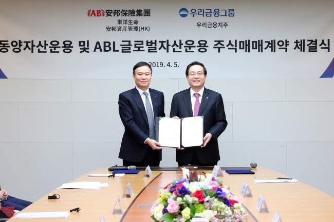 Woori Financial Group Chairman Sohn Tae-seung (right) and Tongyang Life CEO Luo Jianrong pose after signing a stock purchase agreement on Monday. (Woori Financial Group)