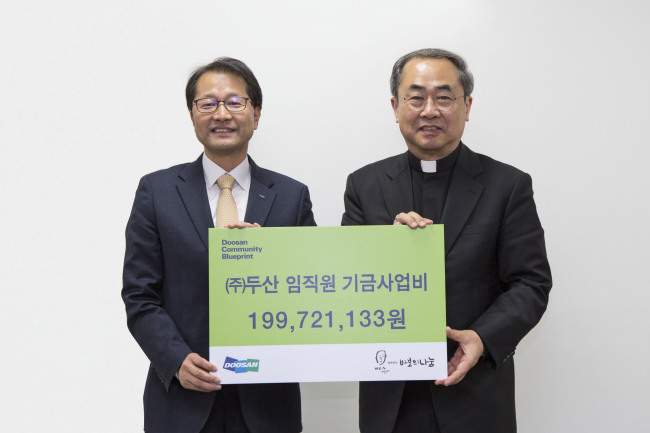 지난 15일 서울 명동성당에서 ㈜두산 김윤건 전무(왼쪽)가 재단법인 바보의나눔 손희송 이사장에게 사회공헌 기부금 약 2억원을 전달한 뒤 기념촬영을 하고 있다. [㈜두산 제공]