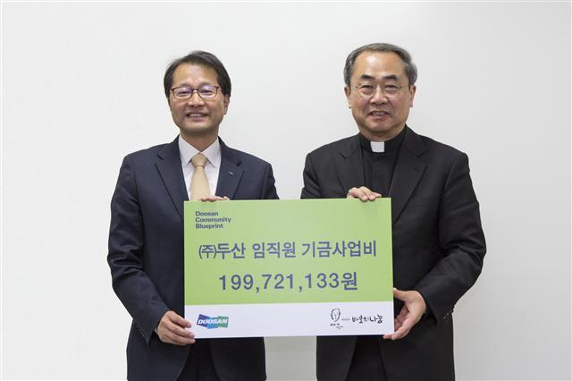 지난 15일 서울 명동성당에서 (주)두산 김윤건 전무(왼쪽)가 재단법인 바보의나눔 손희송 이사장에게 사회공헌 기부금 약 2억원을 전달한 뒤 기념촬영을 하고 있다. [(주)두산 제공]