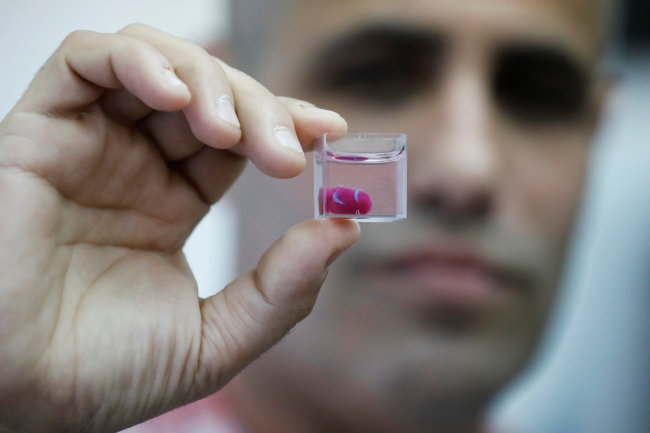 Israeli scientist Tal Dvir from Tel Aviv University holds a transparent cup containing what the university says is the world?s first 3D-printed, vascularised engineered heart, during a demonstration at a laboratory in the university, Tel Aviv, on Monday. (Reuters)