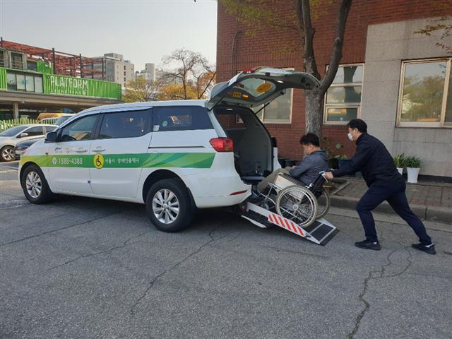 장애인콜택시 기사가 휠체어를 탄 장애인을 택시에 태우고 있다.