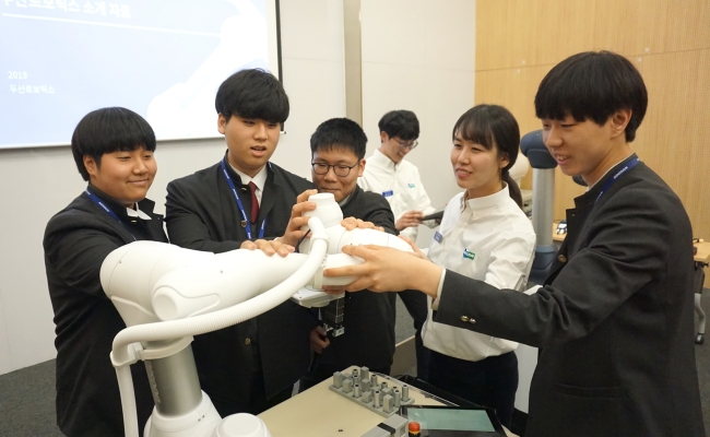 두산로보틱스 본사(경기도 수원)에서 열린 로봇 아카데미에 참가한 삼일공업고등학교 학생들이 두산로보틱스 연구원들과 함께 협동로봇을 시연하고 있다.[두산 제공]