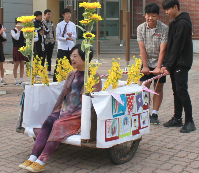 Middle school students in Cheongju, North Chungcheong Province, carry their teacher on a wagon decorated with flowers on Wednesday. (Miwon Middle School/Yonhap)