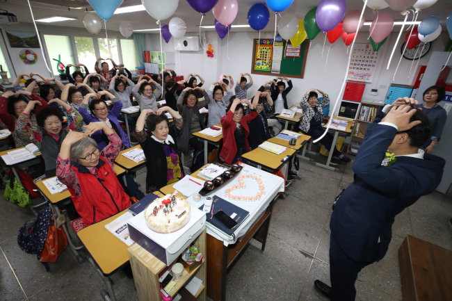 Lifelong learners studying in Seoul make hearts over their heads during a Teachers’ Day event on Wednesday. (Yonhap)