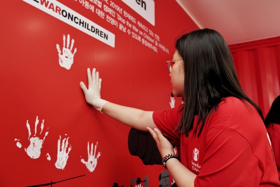 A participant makes handprints on a wall as part of the “Stop the War on Children” campaign. (Save the Children)